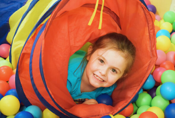 child playing in a tunnel and ball pit